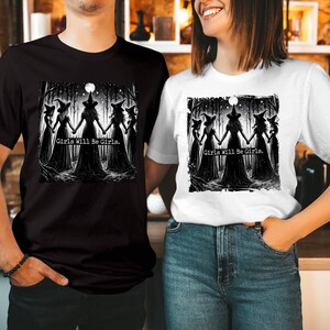 May include: A black t-shirt and a white t-shirt, each featuring a graphic print of five witches in pointed hats holding hands in a forest under a full moon. The text "Girls Will Be Girls." is printed in the center of the illustration on both shirts.