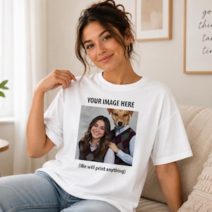 May include: A white short-sleeved t-shirt featuring a custom graphic print on the chest. The print includes the text "YOUR IMAGE HERE" above a photograph of a person and a dog wearing matching argyle vests, with the text "(We will print anything)" below.