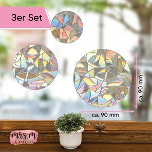 Könnte beinhalten: Ein Set mit drei runden, irisierenden Fensterstickern mit geometrischem Muster. Jeder Sticker hat einen Durchmesser von ca. 90 mm. Das Set ist mit "3er Set" gekennzeichnet.