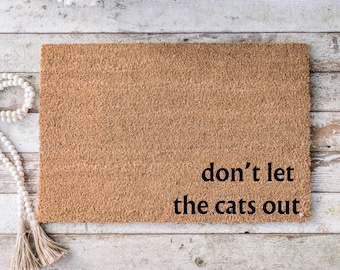 May include: A brown coir doormat with the text "don't let the cats out" in black lettering.