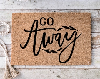 May include: A brown coir doormat with the text "Go Away" in black script lettering with decorative leafy accents.