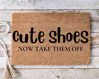 May include: A brown coir doormat with the text "cute shoes now take them off" in black lettering.