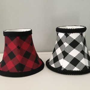 May include: Two lampshades with a black and white buffalo plaid pattern. One lampshade is red and black, and the other is white and black.