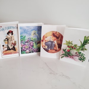 May include: Four greeting cards with vintage botanical and gardening themes. The cards feature illustrations of flowers, a child gardening, and seed packet advertisements. The cards are displayed on a white surface.