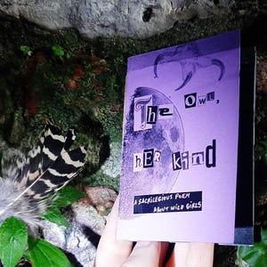 Puede incluir: Un pequeño libro morado titulado "The Owl, Her Kind" con un gráfico de luna. La portada presenta letras recortadas y el subtítulo "A Sacrilegious Poem About Wild Girls". Una pluma y vegetación son visibles en el fondo.