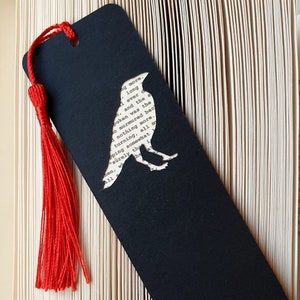 Handmade bookmark inspired by Edgar Allan Poe's poem The Raven. A raven shape cut from on each side of black card reveals a yellowed and aged section of text from the iconic horror classic, and is finished off with a silky red tassel.