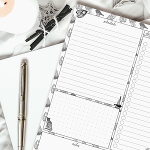 May include: A black and white printable planner with a Halloween theme. The planner has sections for schedule, notes, and a to-do list. The design features a cat, a witch's hat, and other spooky elements.