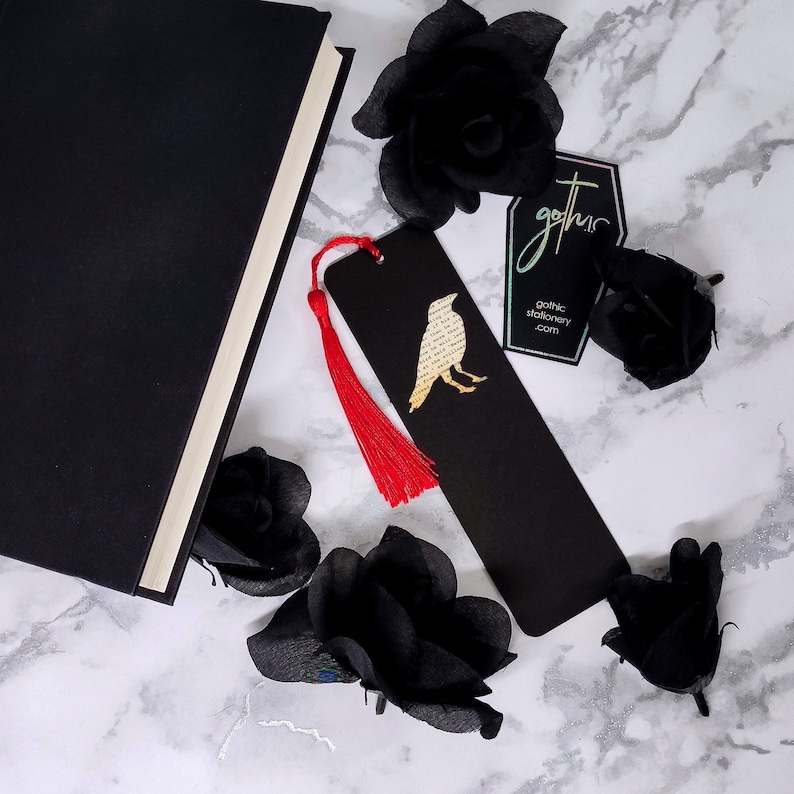 Handmade bookmark inspired by Edgar Allan Poe's poem The Raven. A raven shape cut from on each side of black card reveals a yellowed and aged section of text from the iconic horror classic, and is finished off with a silky red tassel.
