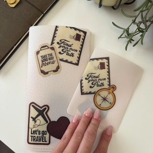 Könnte beinhalten: Zwei transparente Reise-Themen-Beutel mit dekorativen Aufklebern. Ein Beutel hat einen Kofferaufkleber mit dem Text "TAKE THE LONG WAY home". Ein anderer Beutel hat einen Kompassaufkleber und den Text "Find your own Path". Ein dritter Aufkleber sagt "Let's go TRAVEL".