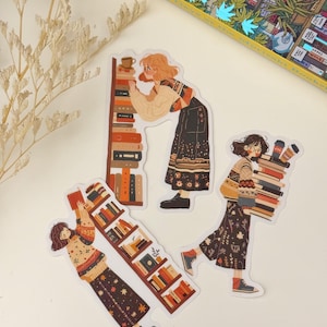 May include: Three illustrated stickers featuring women with books. The stickers are on a white background. The first sticker shows a woman in a brown and white sweater and skirt reaching for a book on a bookshelf. The second sticker shows a woman in a black and white dress holding a stack of books. The third sticker shows a woman in a brown and white sweater and skirt carrying a stack of books.