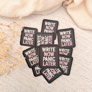 May include: A collection of rectangular embroidered patches featuring a black background with the white text 'WRITE' and 'PANIC' and the pink text 'NOW' and 'LATER'. Each patch displays the phrase 'WRITE NOW PANIC LATER' in a stacked layout.