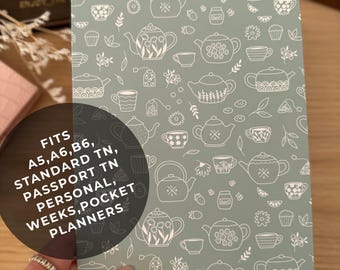 Op de afbeelding: Een lichtgroene planneromslag met een wit theepottenpatroon. Geschikt voor A5, A6, B6, Standard TN, Passport TN, Personal, Weeks en Pocket planners. De tekst "FITS A5, A6, B6, STANDARD TN, PASSPORT TN, PERSONAL, WEEKS, POCKET PLANNERS" is zichtbaar.