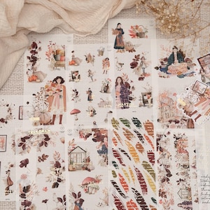 Può includere: Una collezione di fogli di adesivi decorativi con illustrazioni a tema autunnale, tra cui figure in cappotto, zucche, funghi, fogliame e case. I disegni incorporano accenti in lamina d'oro, testo e motivi botanici in calde tonalità autunnali.