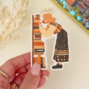 May include: A sticker featuring a cartoon illustration of a person with blonde hair looking at a bookshelf filled with books. The person is wearing a brown and white sweater, black pants, and brown shoes. The bookshelf is brown with orange and red books. The sticker is on a white background.