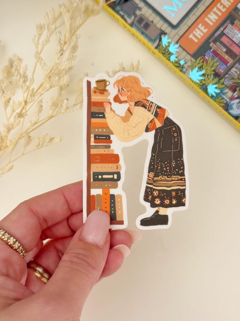 May include: A sticker featuring a cartoon illustration of a person with blonde hair looking at a bookshelf filled with books. The person is wearing a brown and white sweater, black pants, and brown shoes. The bookshelf is brown with orange and red books. The sticker is on a white background.