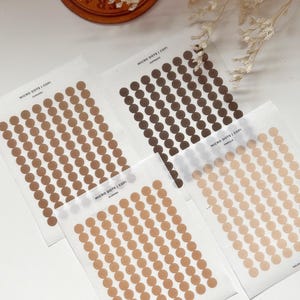 May include: Three sheets of sticker paper with different shades of brown dots. The sheets are labelled "MICRO DOTS | COFI" with the colour names "CARAMEL", "ALMOND", and "VANILLA".