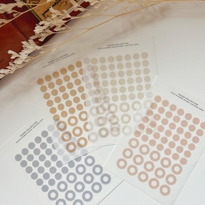 Könnte beinhalten: Vier Blätter Klebepapier mit Punkten und Ringen in verschiedenen Farben. Die Aufkleber sind mit "Shape Collection Dots & Rings Stickers | 4 Colour Caps" beschriftet.