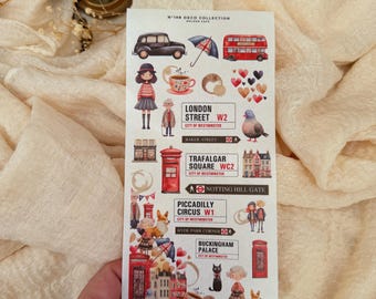 Op de afbeelding: Een vel met stickers met een Londens thema, met iconische afbeeldingen zoals een rode dubbeldekkerbus, een zwarte taxi en rode telefooncellen. De stickers bevatten ook illustraties van mensen, harten en bezienswaardigheden zoals Buckingham Palace en Trafalgar Square.