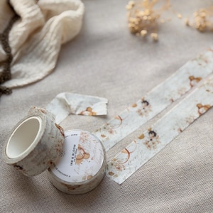 Op de afbeelding: Twee rollen decoratieve washi tape met een vintage bloemen- en berenontwerp. Eén rol is afgerold en toont het patroon van de tape. De tape is gelabeld met "INK & BLOOM". De tape is 20 mm breed.