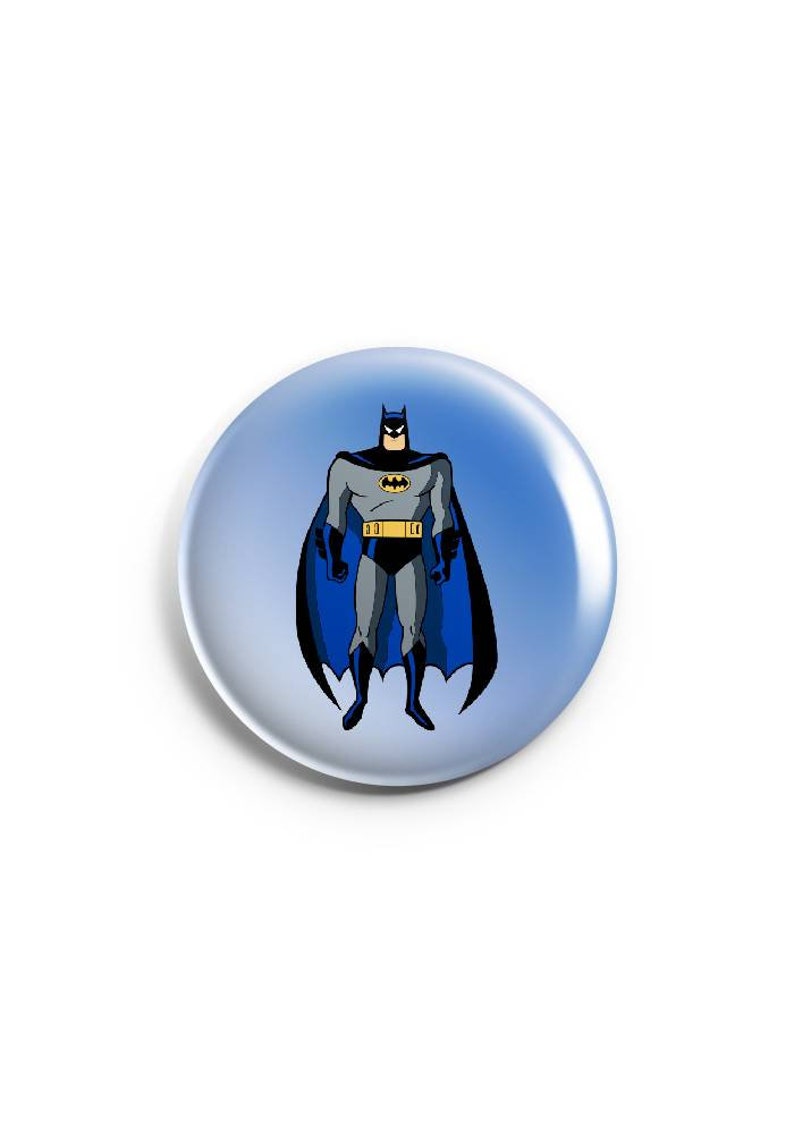 May include: A round button with a blue background and a cartoon image of Batman in a black suit with a yellow belt and a blue cape. The image is on a white background.