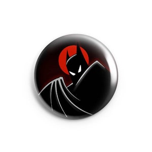 May include: A black and white illustration of Batman in front of a red sun. Batman is wearing a black cape and cowl. The image is on a button.