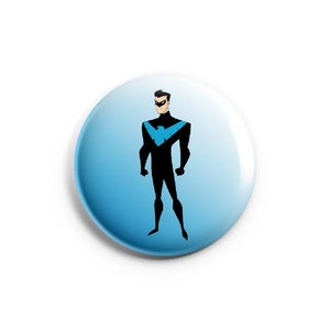 May include: A blue and black button with a cartoon image of a superhero wearing a black suit with a blue bird logo on the chest.