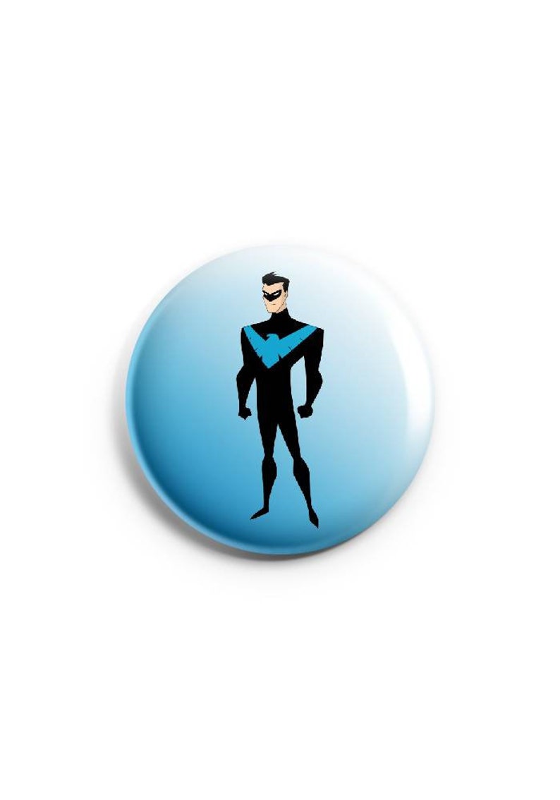 May include: A blue and black button with a cartoon image of a superhero wearing a black suit with a blue bird logo on the chest.