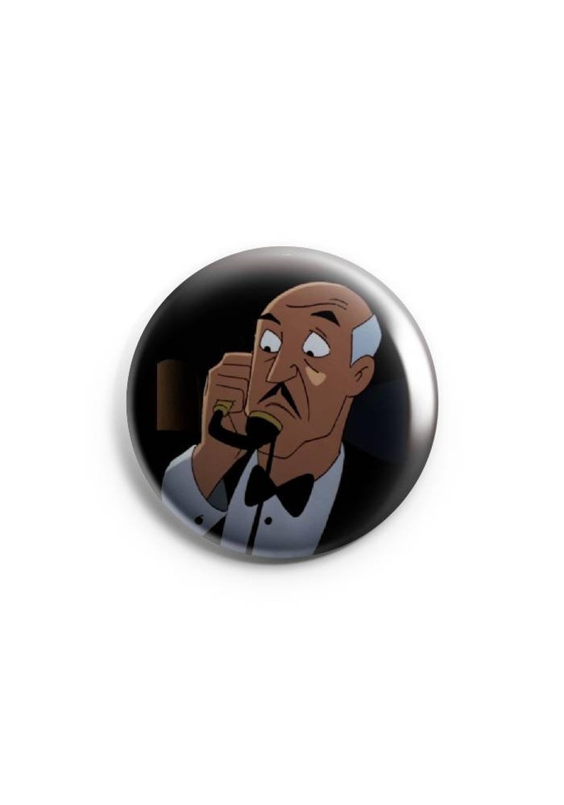 May include: A black and white button featuring a cartoon character with a white mustache and a bow tie. The character is wearing a tuxedo and has a surprised expression on their face.
