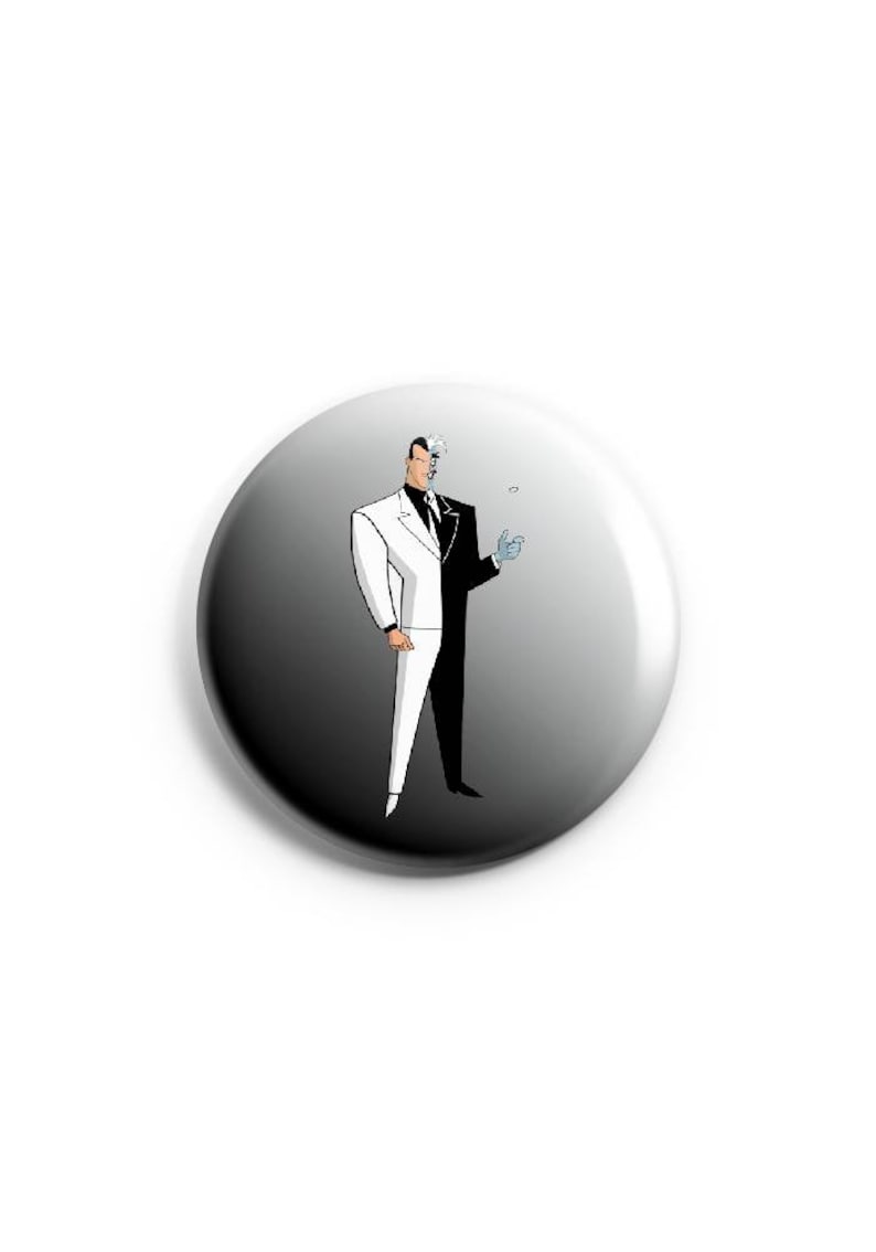 May include: A black and white button with a cartoon image of Two-Face from Batman. Two-Face is wearing a white suit and a black suit, with a line down the middle of his face.