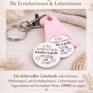 Puede incluir: Un llavero rosa y plateado con dos colgantes circulares blancos. Los colgantes tienen el texto "KLEINE MENSCHEN brauchen so gro&szlig;e HERZEN wie DEINS!" en color. Un regalo atento.