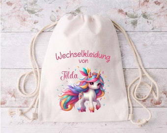 Könnte beinhalten: Ein weißer Kordelzugbeutel mit einer bunten Einhorn-Illustration und dem Text "Wechselkleidung von Tilda".