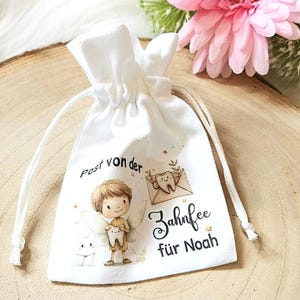 May include: White drawstring bag with a tooth fairy illustration and the text "Post von der Zahnfee f&uuml;r Noah".
