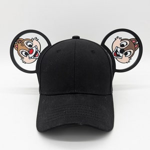 May include: Black baseball cap with cartoon character ears. The ears are black with a white outline and feature a cartoon image of Chip from Disney's Chip and Dale.