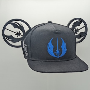 May include: Black baseball cap with a blue Rebel Alliance symbol and black Mickey Mouse ears. The ears are shaped like the Rebel Alliance symbol.