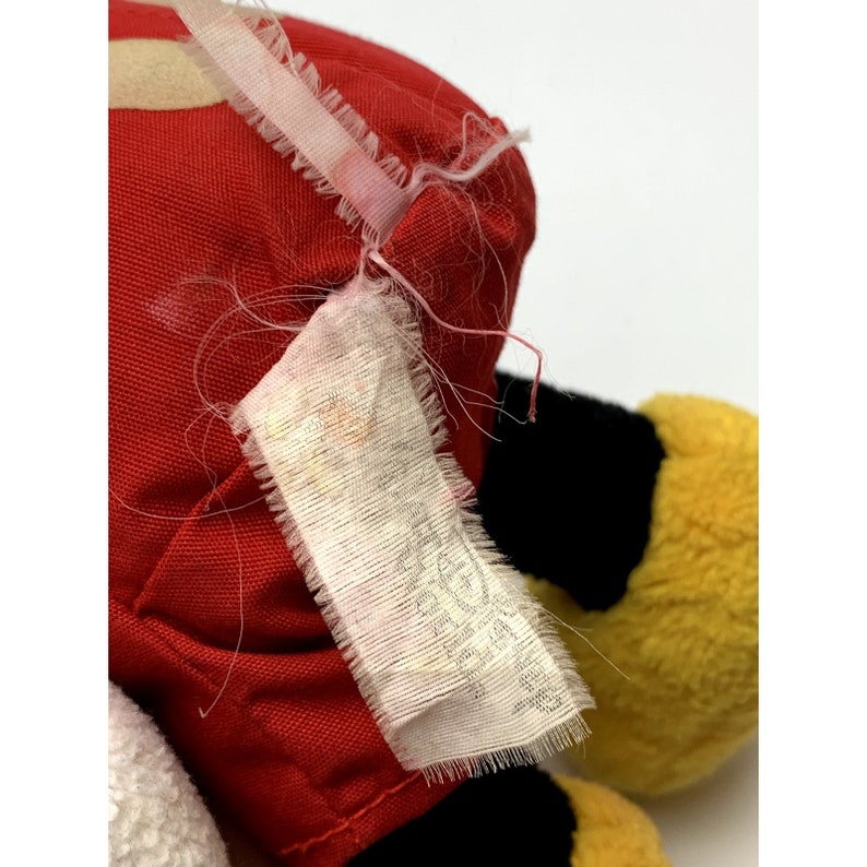 May include: A red, black, and yellow plush toy with a white tag that says "Made in China".