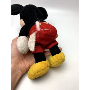 May include: A black and red plush Mickey Mouse toy with yellow shoes. The toy is in good condition, but the red shorts have some wear and tear.