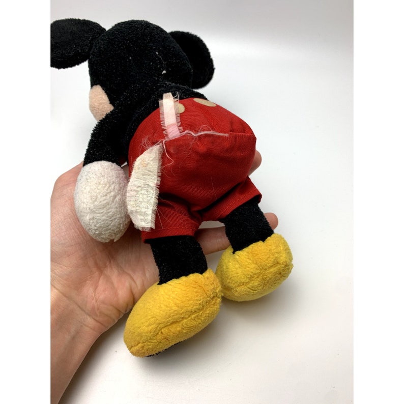 May include: A black and red plush Mickey Mouse toy with yellow shoes. The toy is in good condition, but the red shorts have some wear and tear.