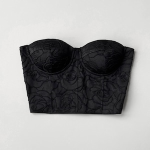 May include: A black strapless corset with a floral design. The corset is made of a textured fabric and has a boned structure.