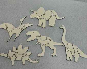 May include: Five wooden dinosaur puzzle pieces, including a stegosaurus, a brachiosaurus, a pterodactyl, a triceratops, and a tyrannosaurus rex. The pieces are all cut out in a jigsaw style and are ready to be assembled.