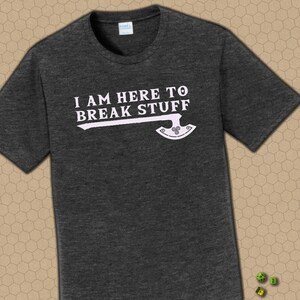 May include: Dark gray t-shirt with the phrase "I AM HERE TO BREAK STUFF" in white, accompanied by a stylized axe graphic. The shirt is made of a soft material and has a crew neck.