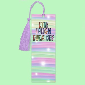Pode incluir: Um marcador de livros retangular com um design de listras pastel em tons de rosa, azul, verde e roxo. O texto "LIVE LAUGH FUCK OFF" é impresso em letras coloridas. Uma borla e um cordão de lavanda são presos no topo.