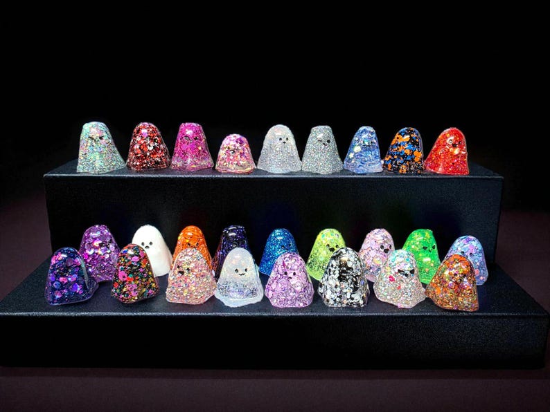 Collection of small glittery resin ghost figurines in different colours, displayed on black steps for a lucky dip random selection
