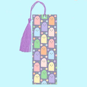 May include: A rectangular bookmark with a purple background featuring smiling ghost illustrations in various pastel colors. The bookmark has a matching purple tassel and cord for easy placement in books. Floral accents are also present.
