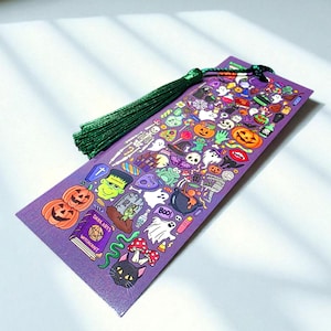 Puede incluir: Un marcap&aacute;ginas morado con tem&aacute;tica de Halloween y borla verde. El marcap&aacute;ginas est&aacute; cubierto de ilustraciones coloridas de calabazas, fantasmas, Frankenstein y otras im&aacute;genes espeluznantes. Las palabras "DARK ARTS" y "WITCHCRAFT" son visibles en un libro.
