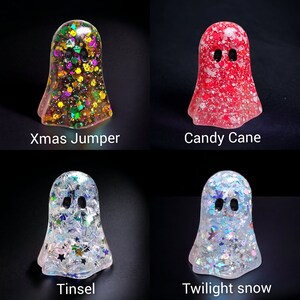 May include: Four resin ghost figurines with glitter and text. The "Xmas Jumper" ghost has colorful glitter. The "Candy Cane" ghost is red with white specks. The "Tinsel" ghost has silver stars. The "Twilight snow" ghost has blue and silver glitter.