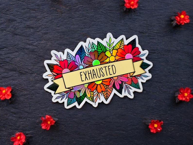 May include: A colorful sticker featuring a floral design with the word "EXHAUSTED" on a banner. The sticker showcases a variety of flowers in shades of red, orange, yellow, pink, and purple, with green leaves. The sticker is on a dark surface.