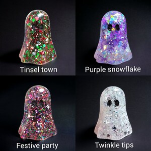 May include: Four resin ghost figurines with glitter and text. The ghosts are in the colors of red, green, purple, and white. The text reads "Tinsel town", "Purple snowflake", "Festive party", and "Twinkle tips".
