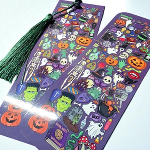 Puede incluir: Dos marcap&aacute;ginas morados con tem&aacute;tica de Halloween con borlas verdes. Los marcap&aacute;ginas est&aacute;n cubiertos de ilustraciones coloridas de calabazas, fantasmas, esqueletos y otros elementos espeluznantes. El texto "DARK ARTS" y "WITCHCRAFT" es visible en un libro.