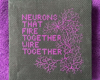 May include: A black canvas with pink embroidery depicting a brain-like structure with the text "NEURONS THAT FIRE TOGETHER WIRE TOGETHER".