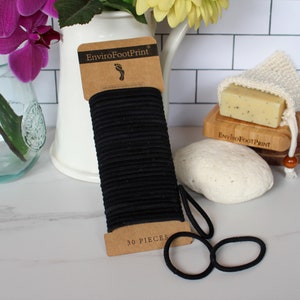 May include: A pack of 30 black hair elastics, labelled "EnviroFootPrint" and "30 PIECES".
